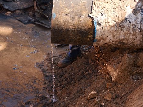 Rusty Old Iron Pipe With Clear Water Flowing From It. Waste water drain pipe in clay