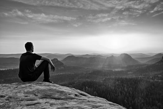 Tall hiker in mountains. Thinking man silhouette in nature within daybreak. The vignetting effect.Black and white photo