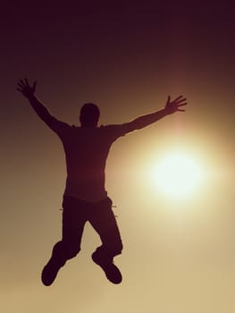 Jumping man. Young crazy man is jumping on red sky background.Silhouette of jumping man and beautiful sunset sky. Element of design. Vintage effect.