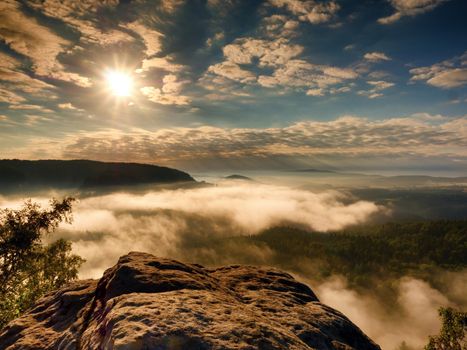 Landscape view. Exposed sandstone cliff above deep misty valley in Saxony Switzerland. Dreamy mood within daybreak after stormy night.