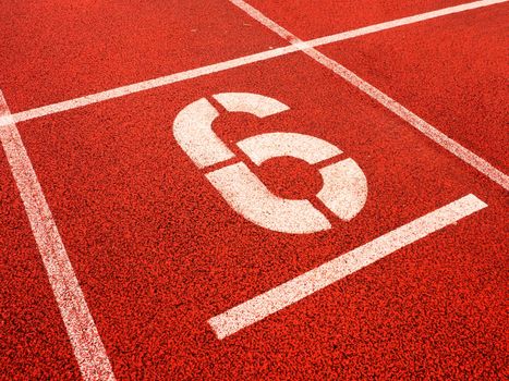 Number six. White athletic track number on red rubber racetrack, texture of running racetracks in stadium