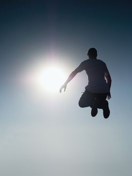 Man fly in air. Blue  Toned effect. Man falling down with raised arms. Sun and colorful sky background. Toned effect