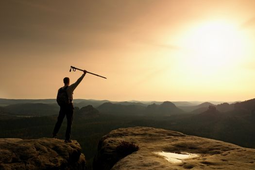 Tourist with poles in hands stand on rock watching  for next step. Sunny spring daybreak in mountains.Vignetting effect.. 