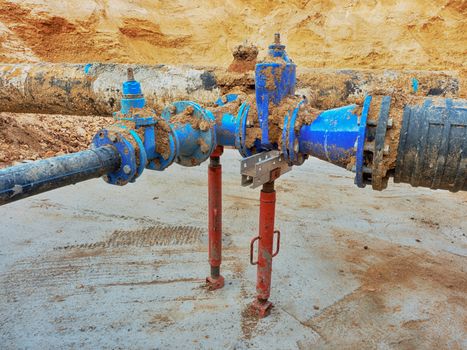 Old big drink water pipes joined with new blue gate valves and reduction joint members. Finished repaired piping waiting for covering by clay. Extreme kind of corrosion, metal corroded texture.