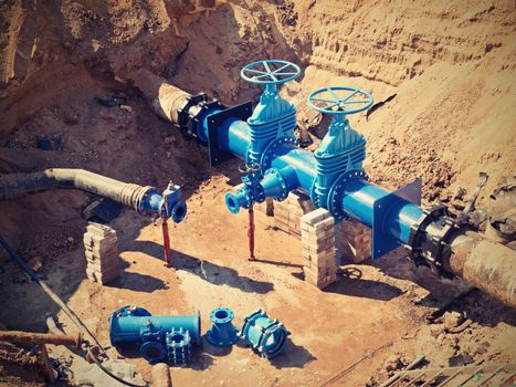 Oil, gas, water industry. Wellhead with valve armature underground. Dug deep trench utilities engineering urban systems.