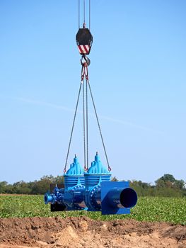 Crane handling 500mm pipe with gate valves. Construction process to restore drink water supply. Spare parts piping on crane chain