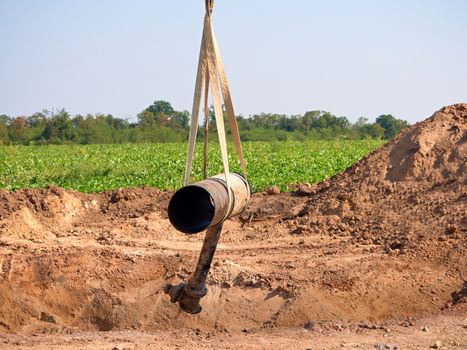 Hanging old tube on crane rope. Clear blue sky in background