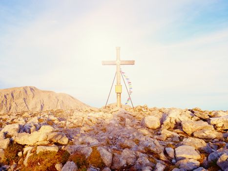 Traditional cross at mountain top in Alp. Cross on top of a mountains peak, monument to the dead climbers. Fresh  wind and gentle clouds in blue sky.
