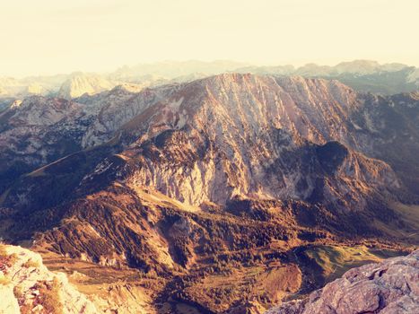 Lens flare light, strong effect. Morning sun between sharp rocks,  Alpine  cliff above valley. Daybreak Sun at horizon. Mountains background