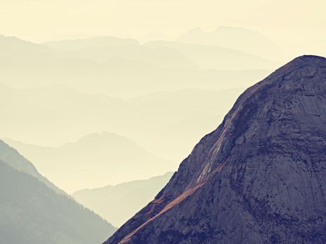 Spectacular aerial view of mountain silhouettes and misty valleys. Misty awaking of beautiful fairy valley. Peaks of rocks cut creamy foggy clouds.