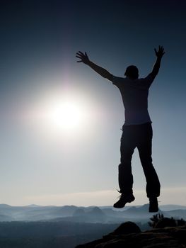 Jumping man. Young crazy man is jumping on colorful sky background.Silhouette of jumping man and beautiful sunset sky. Element of design. Vintage effect.