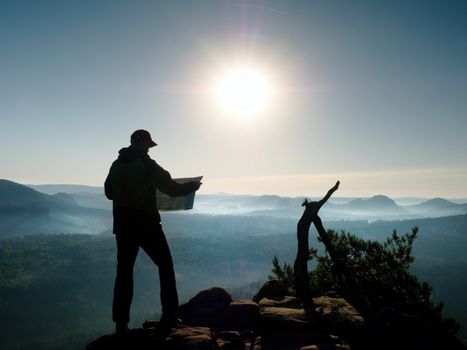 Silhouette of hike guide looking in paper  map in nature while hiking.  Man hiker with heavy backpack. Vintage Style Toned effect