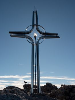 Praying summit cross on high rocky mountain. Steel artistic crucifix on top of Alpine mountain,  in the Dolomite Alps 