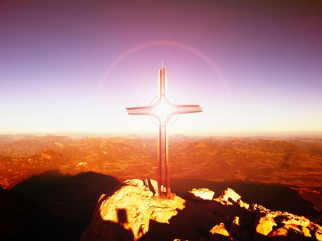 Lens flare light, strong effect.  Cross on peak of Hoher Goell. Iron crucifix at mountain top in Alp at Austria Germany border.  View to Tennen Range and Dachstein range, Berchtesgaden Alps. 