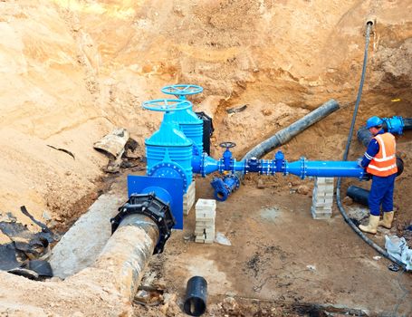 Worker in protective workwearunderground on gate valve, reconstrucion of drink water system