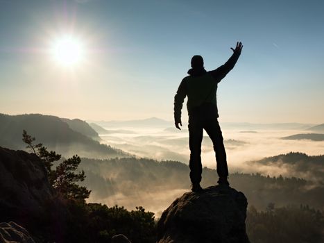 Man silhouette stay on sharp rock peak. Satisfy hiker enjoy view. Tall man on rocky cliff watching down to landscape. Vivid and strong vignetting effect.