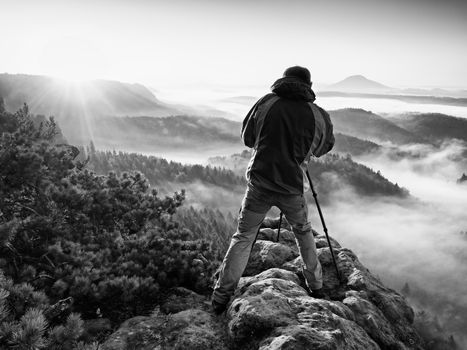 Photograph silhouette  take photo. Man enjoy  photography of  fall daybreak in nature on cliff on rock. Autumnal foggy landscape, misty sunrise.