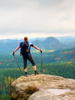 Alone tourist with outdoor sportswear and backpack stand on cliff edge  and watching into colorful autumn valley bellow.  Vintage Style Toned effect