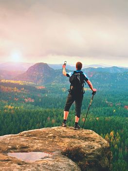 Tourist with big backpack stand on rocky view point and watching to colorful autumnal landscape. Tourist traveler on view point.  Hiker looking  horizon in trip in  fall country