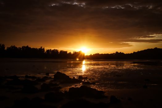 Beautiful sunset on the beach and sun is reflected on the waves.