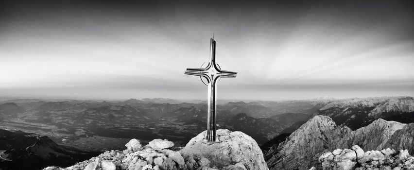 Hoher Goell autumn daybreak panorama. Iron cross at mountain top in Alp at Austria Germany border.  View to Tennen Range and Dachstein range, Berchtesgaden Alps.