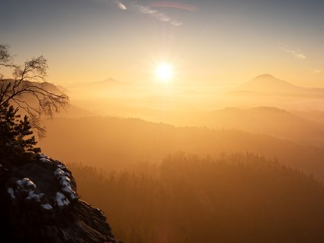 Red daybreak. Misty sunrise in the mountains, the gradation of color clouds. Misty daybreak in a beautiful hills. Peaks of hills are sticking out from foggy background, the fog is red and orange