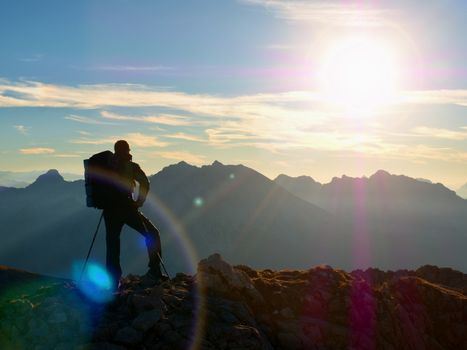 Lens flare light, strong effect. Bow light circles.  Hiker takes selfie photo. Tourist at mountain peak. Daybreak horizon above blue foggy valley. Mountains increased from humidity