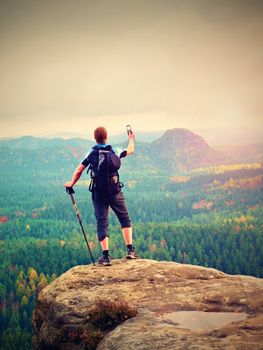 Alone tourist with outdoor sportswear and backpack stand on cliff edge  and watching into colorful autumn valley bellow.  Vintage Style Toned effect