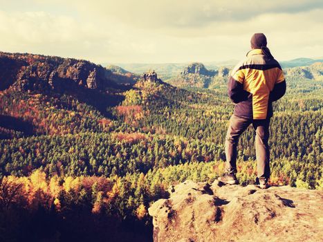 Man stay on sharp rock peak. Satisfy hiker enjoy view. Tall man on rocky cliff watching down to landscape. Vivid and strong vignetting effect.