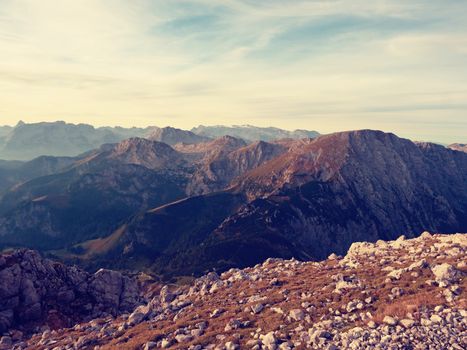 Lens flare light, strong effect. Morning sun between sharp rocks,  Alpine  cliff above valley. Daybreak Sun at horizon. Mountains background
