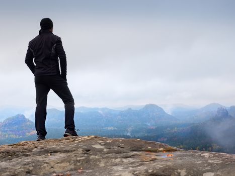 Hiker on sharp cliff of sandstone rock in rock empires park and watching over misty and foggy spring valley