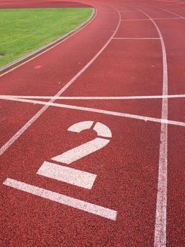 Number two. Big white track number on red rubber racetrack. Gentle textured racetracks in small outdoor stadium.