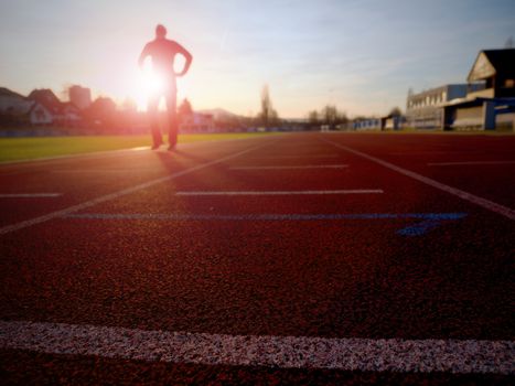 Marathon man training.  Sportsman in running clothes on stadium at sunset. Sport and healthy lifestyle concept and jogging civic training workout