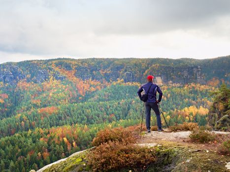 Hiker in sportswear stand on the peak of sandstone rock in rock empires park and watching over the autumnal colorful valley to Sun. Beautiful colors, the  miracle of nature 