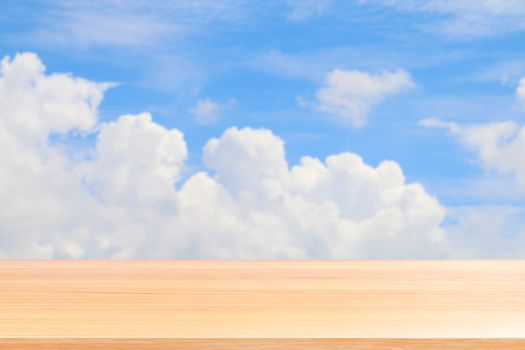 empty wood table floors on blurred blue sky and cloud background, wood table board empty front blur sky blue, wooden plank blank on sky with perspective brown wood table for mock up display products