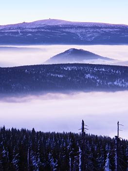 Far mountain peak with observatory above creamy mist. Shinning lights on antenna. Wavy fog in vally bellow, inverse winter weather.