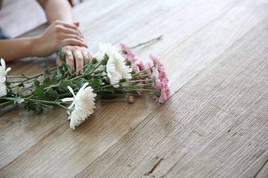 daisies flowers on wood with girl hand