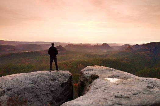 Hiker on the peak of sandstone rock in rock empires park and watching over the misty and foggy morning valley to horizon.