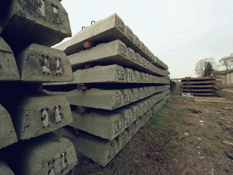 Sleepers stock in railway depot. New concrete railway ties stored for reconstruction of old railway station. Old houses  in background