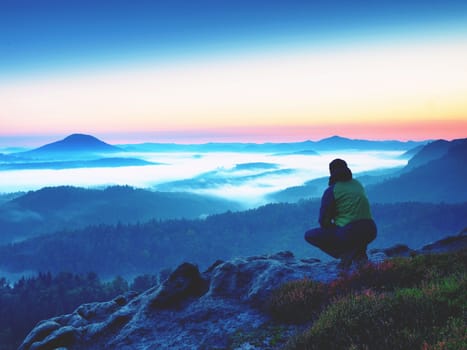 Hiker  man on rock watch over creamy mista and foggy morning landscape. Beautiful fall morning. Autumn hilly cvountryside