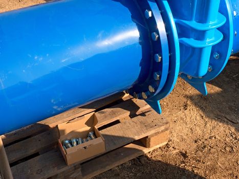 Detail of 500mm big new drink water joint unit with screws and nuts. Collar pipe fitting. Piping repair,  fasteners and spare parts on wooden pallet .