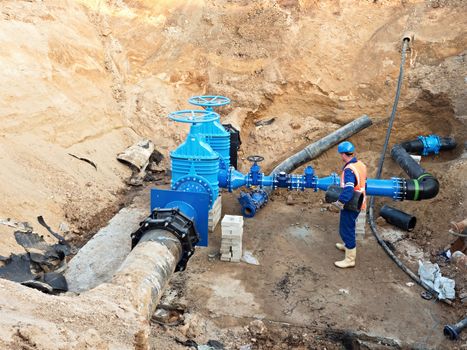 Worker works underground for reconstrucion of drink water system. Technical expert at  gate valve on new pipeline system check of repaired connection before covering by clay