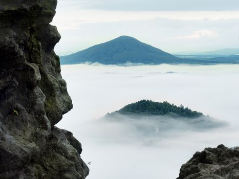 Spring misty landscape. Early morning ina beautiful mountains of Bohemian-Saxony Switzerland. Peaks of hills increased from heavy creamy fog. 