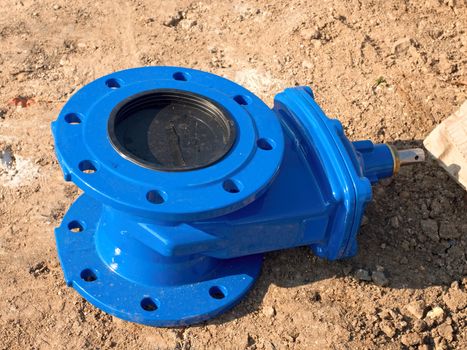 Detail of fittings, 150mm gate valves for drink water system. Repairing of piping in excavation pit. New blue painted gate valve on dry clay