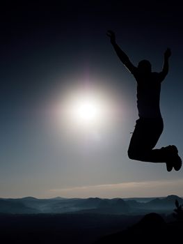 Jumping man. Young crazy man is jumping on colorful sky background.Silhouette of jumping man and beautiful sunset sky. Element of design. Vintage effect.