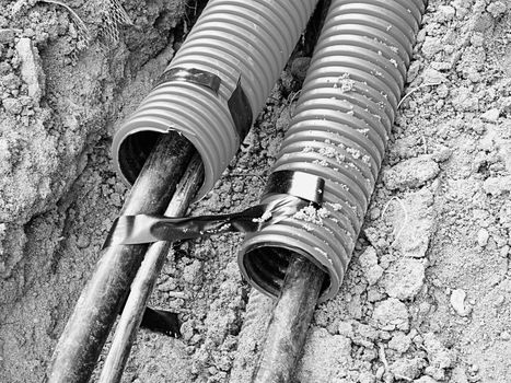 Excavation of trench  with black cables in protective HDPE tube. Lines of metallic and fiber optic cables, building of communication optical network. The installation of connection. 