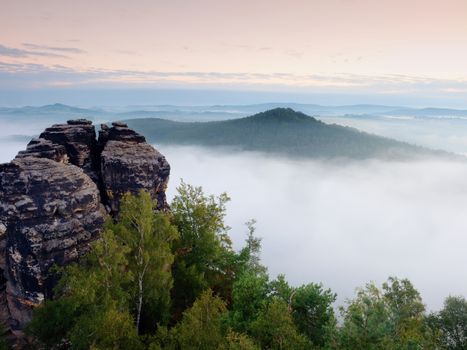 Sharp sandstone cliffs above deep misty valley. Popular climbers resort. Rocks sticking up from fogy lanscape to sky
