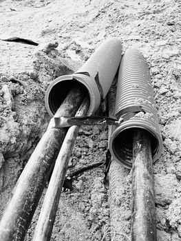 Excavation of trench  with black cables in protective HDPE tube. Lines of metallic and fiber optic cables, building of communication optical network. The installation of connection. 