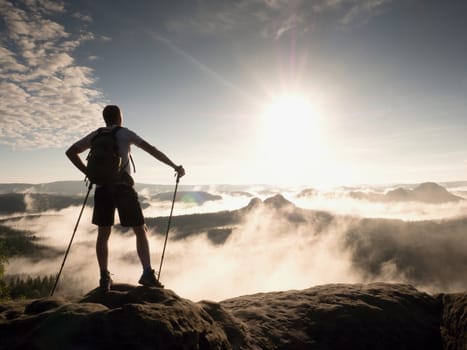 Hiker with backpack reaches the summit of mountain peak. Success, freedom and happiness, achievement in mountains. Active sport concept.