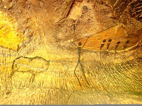 Buffalo hunting. Paint of human hunting on sandstone wall, prehistoric picture. Black carbon abstract children art in sandstone cave. Spotlight shines on caveman painting in cave